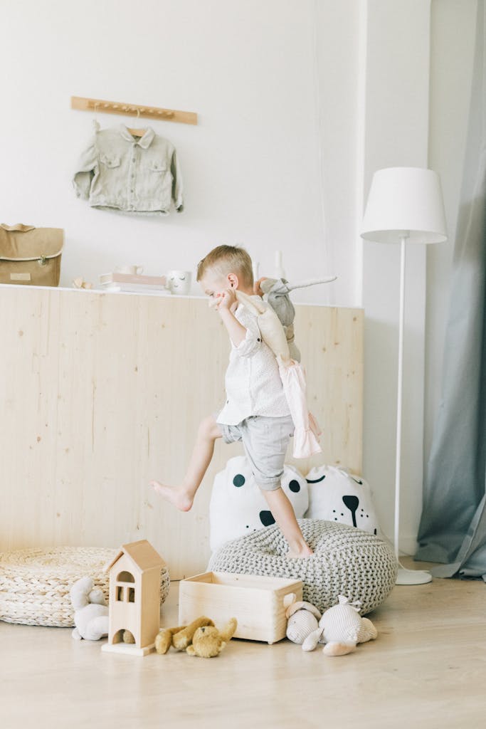 A young child in a light-filled nursery jumps joyfully amidst toys, radiating innocence and fun.