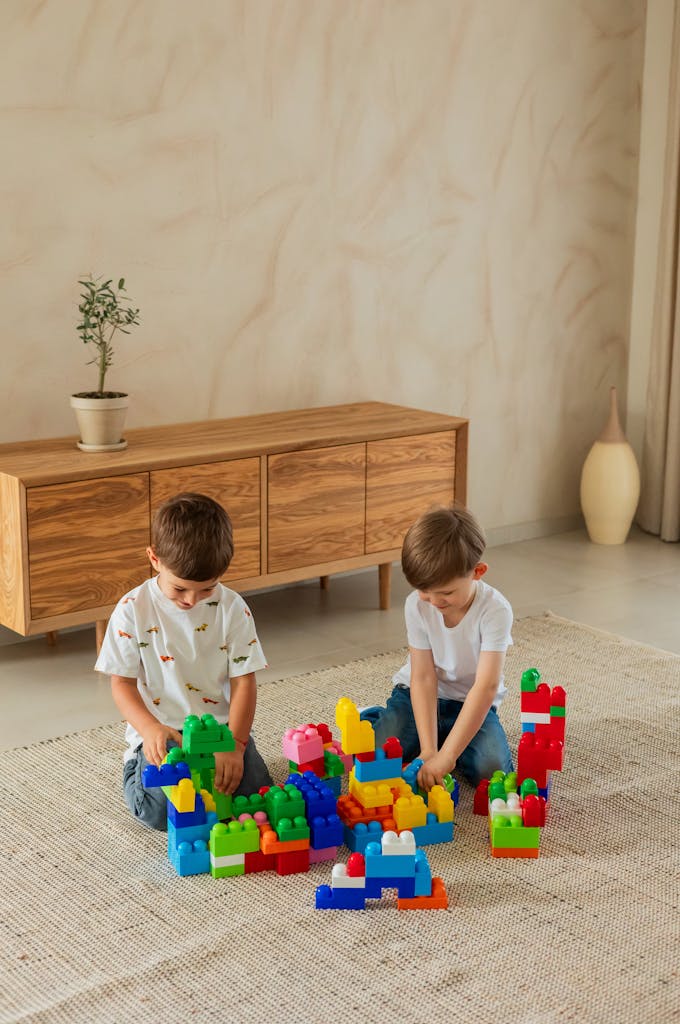Two young boys playing with colorful building blocks on a rug indoors, fostering creativity and fun.