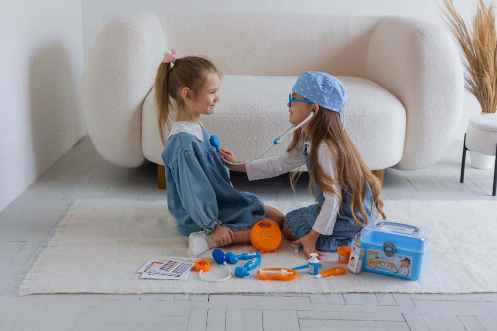 Two young girls role-playing as doctor and patient using a toy medical kit in a cozy room.